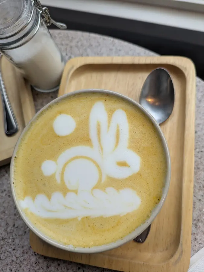 Latte-Art in Form eines Hasen auf einem gelben Milchgetränk