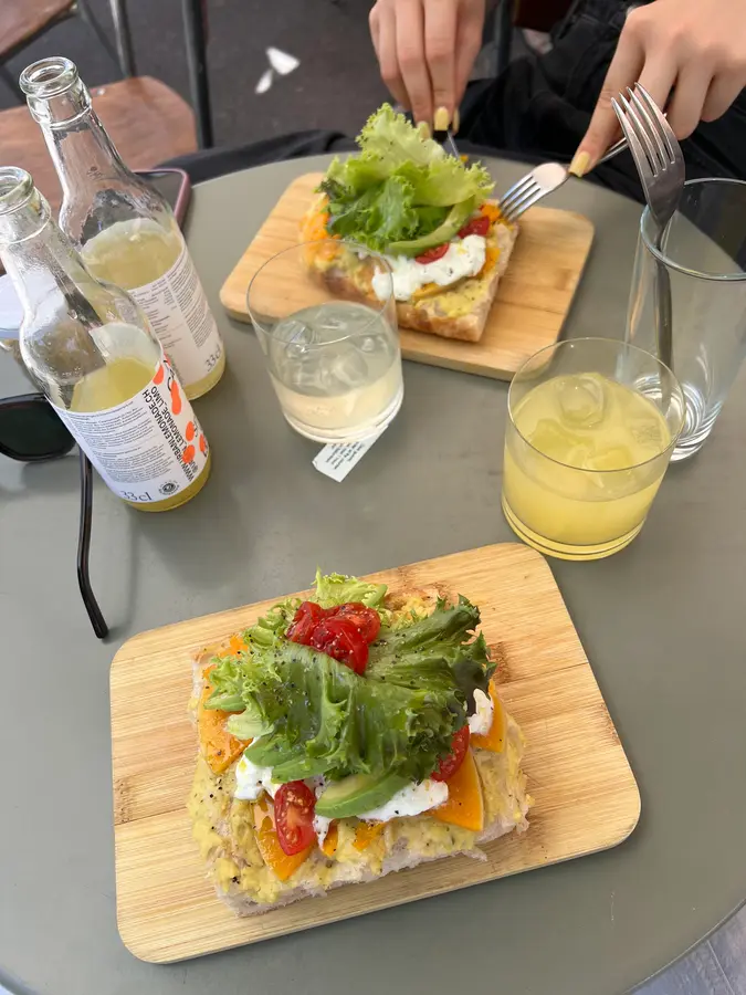 Belegte Focaccia mit Avocado, Tomaten und Salat auf Bambusbrett, dazu Limonade