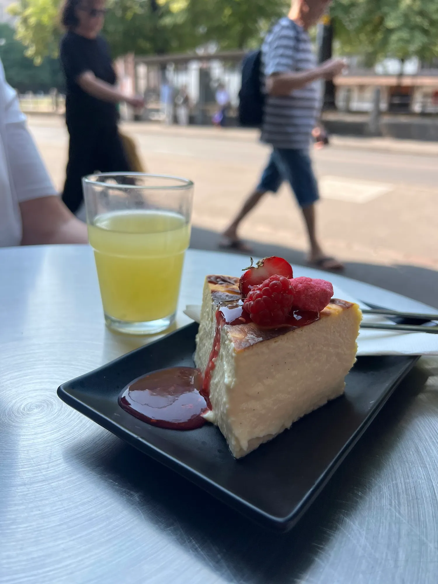 Draussen am Bistrotisch: San Sebastián Cheesecake mit Beeren und eine Limonade, im Hintergrund die Strasse